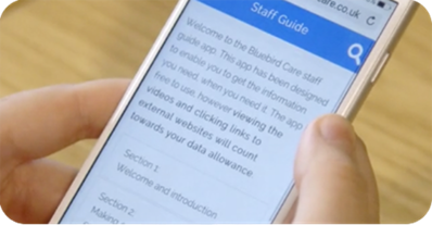 A close up of a white iPhone being held in someone's hands with the Staff Guide app open.