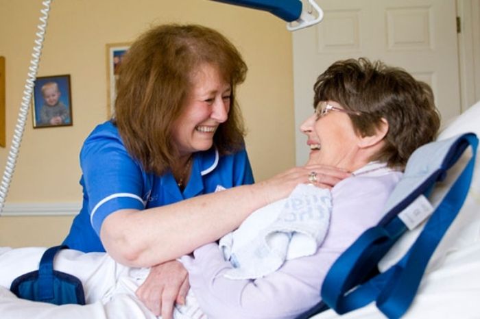 A carer looks after a patient in a bed