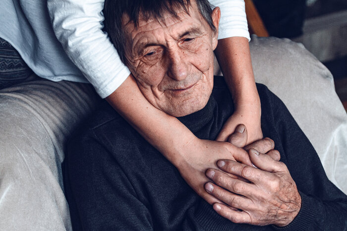 An elderly man with dementia gets comfort from a carer