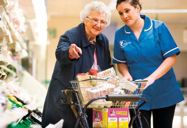 Bluebird Care assistant helping elderly lady with shopping