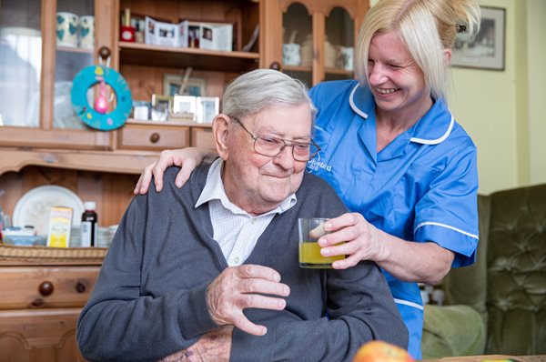 older man receiving domiciliary care from a care assistant