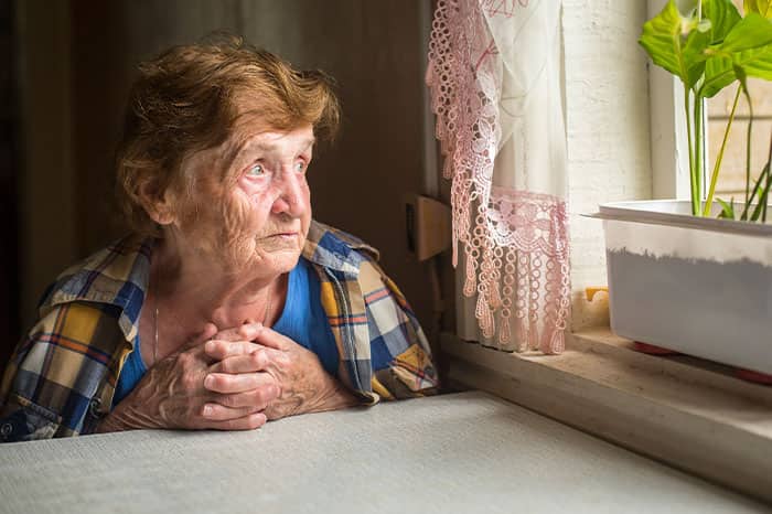 A lonely old woman stares out of the window