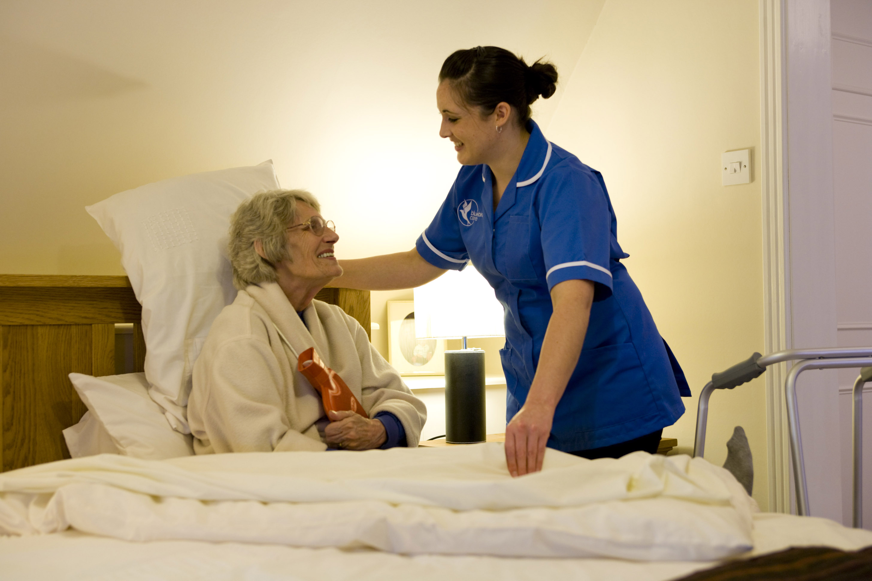 Live-in care, carer helping person in bed