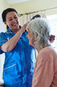 Home care assistant brushing customers hair