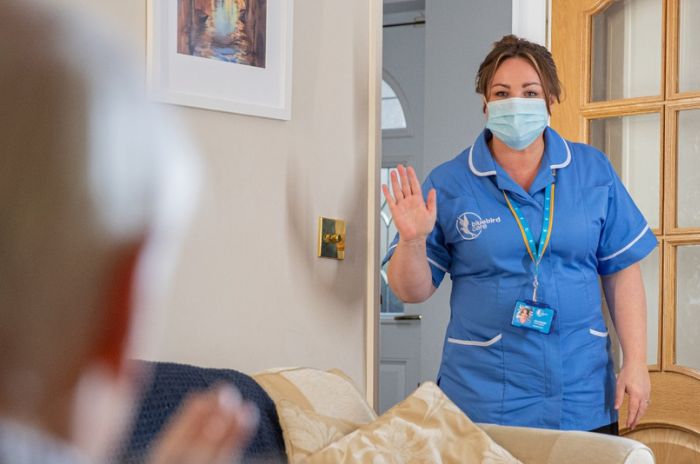 A care assistant waves to a customer as she arrives for her shift
