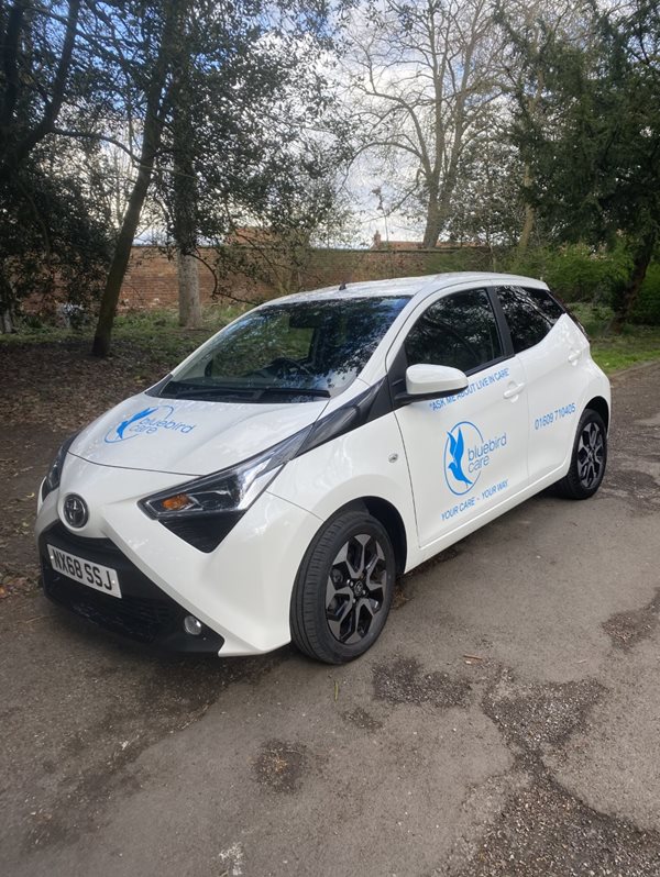 A white Toyota Aygo car with Bluebird Care Logo's on it