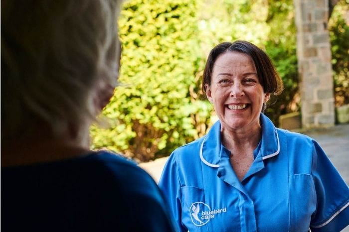 A carer is welcomed at the door by a customer