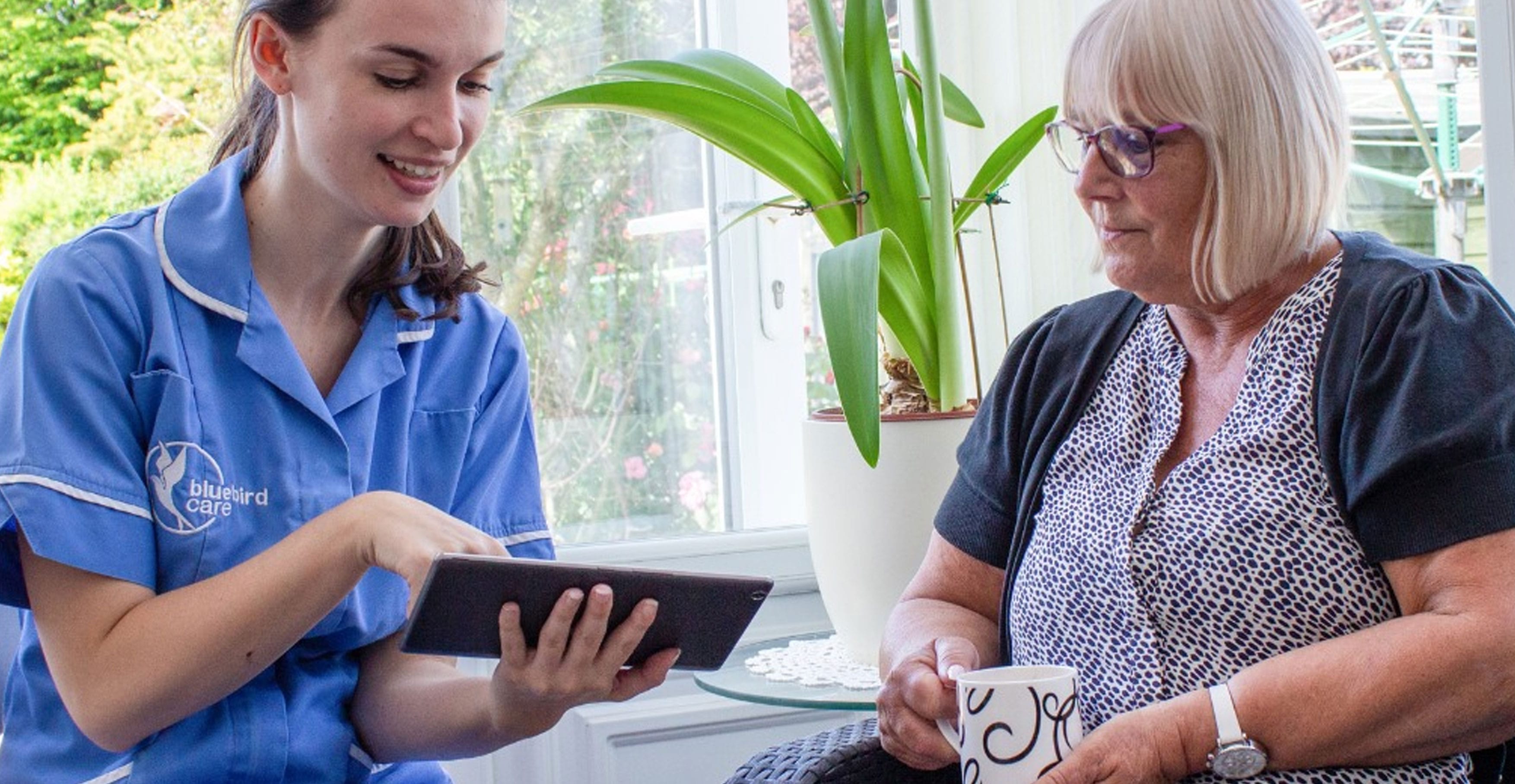 Blue Bird Care assistant showing her tablet to a lady