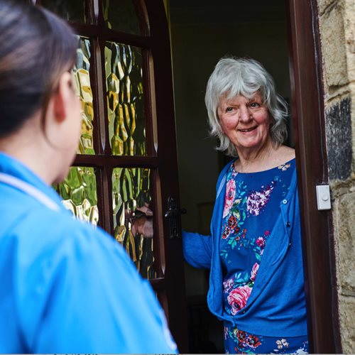 Happy customer opening the door to a Blubeird Care live-in care assistant