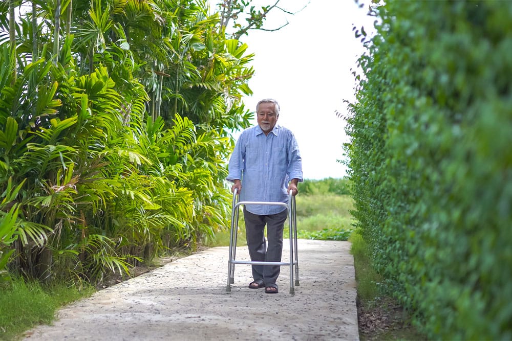 happy old man walking through tropical garden