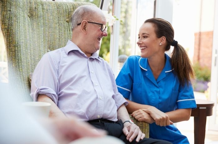 A smiling care worker chats with a laughing elderly gentleman