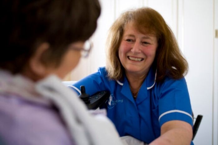A smiling carer looks after a patient